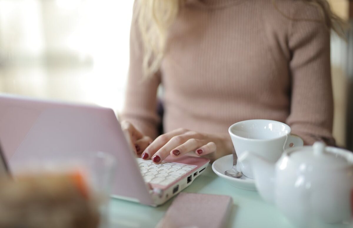A freelancer in a cozy setting using a laptop with a cup of coffee nearby. Ideal for remote work themes.